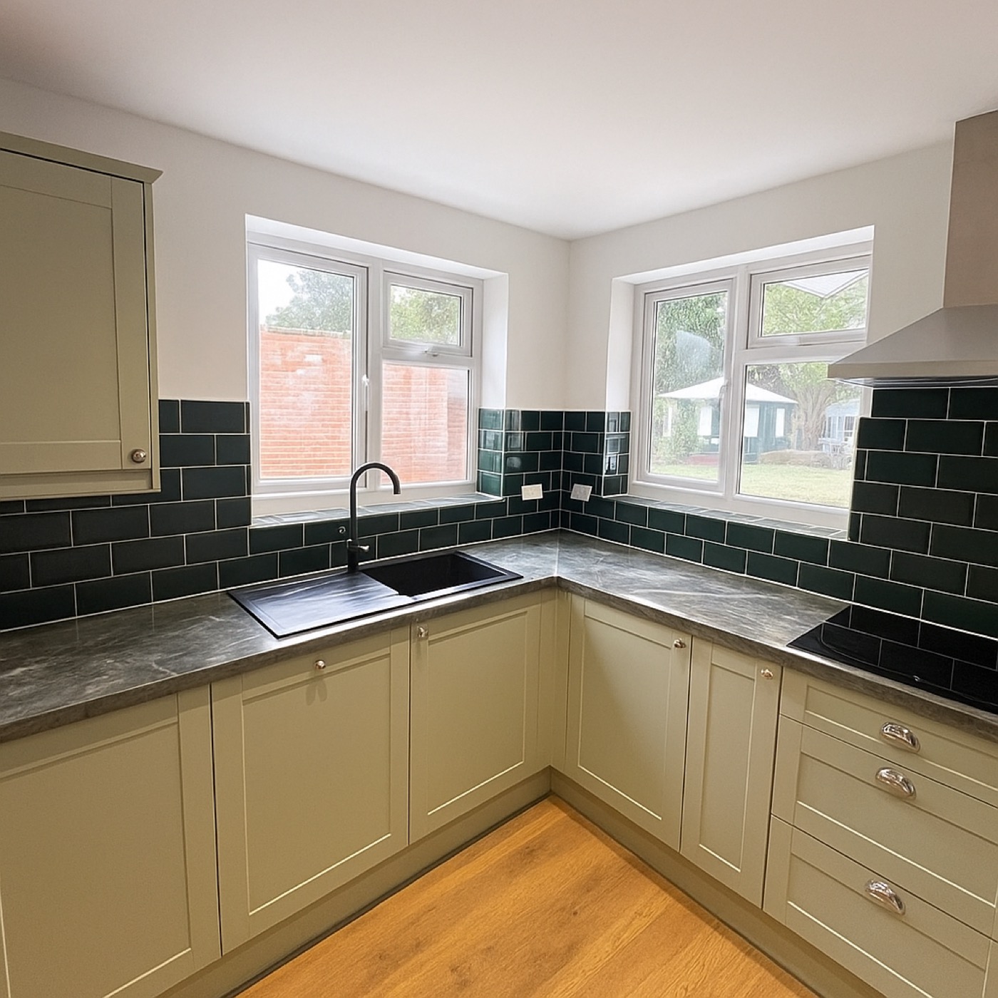 Sage green shaker kitchen with dark marble worktops and green metro tiles
